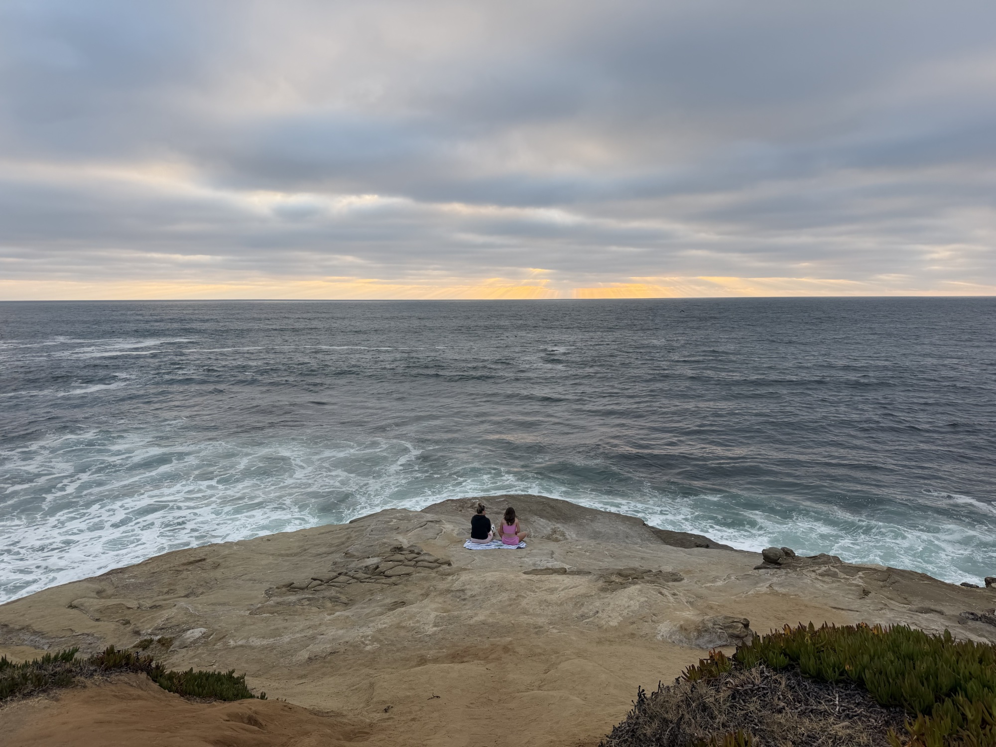 Two visitors sitting above the Pacific Ocean along the San Diego coast